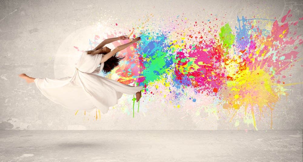 Happy teenager jumping with colorful ink splatter on urban background concept